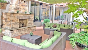 An outdoor patio area with stone walls, wicker furniture, and string lights. - Crowne Plaza Portland Downtown Convention Center by IHG (Portland)