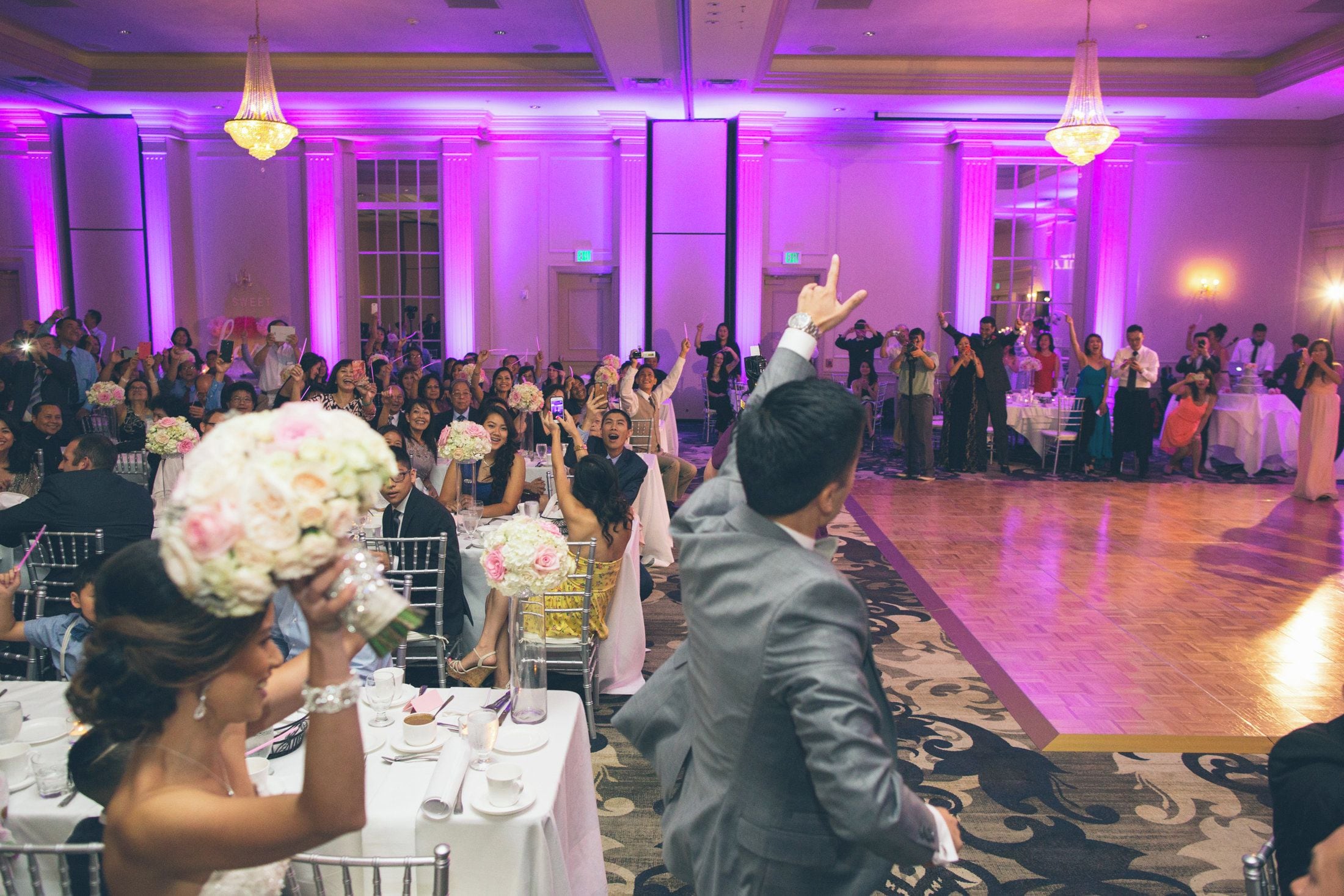 Una recepción de boda con invitados sentados en mesas, una pista de baile y candelabros.