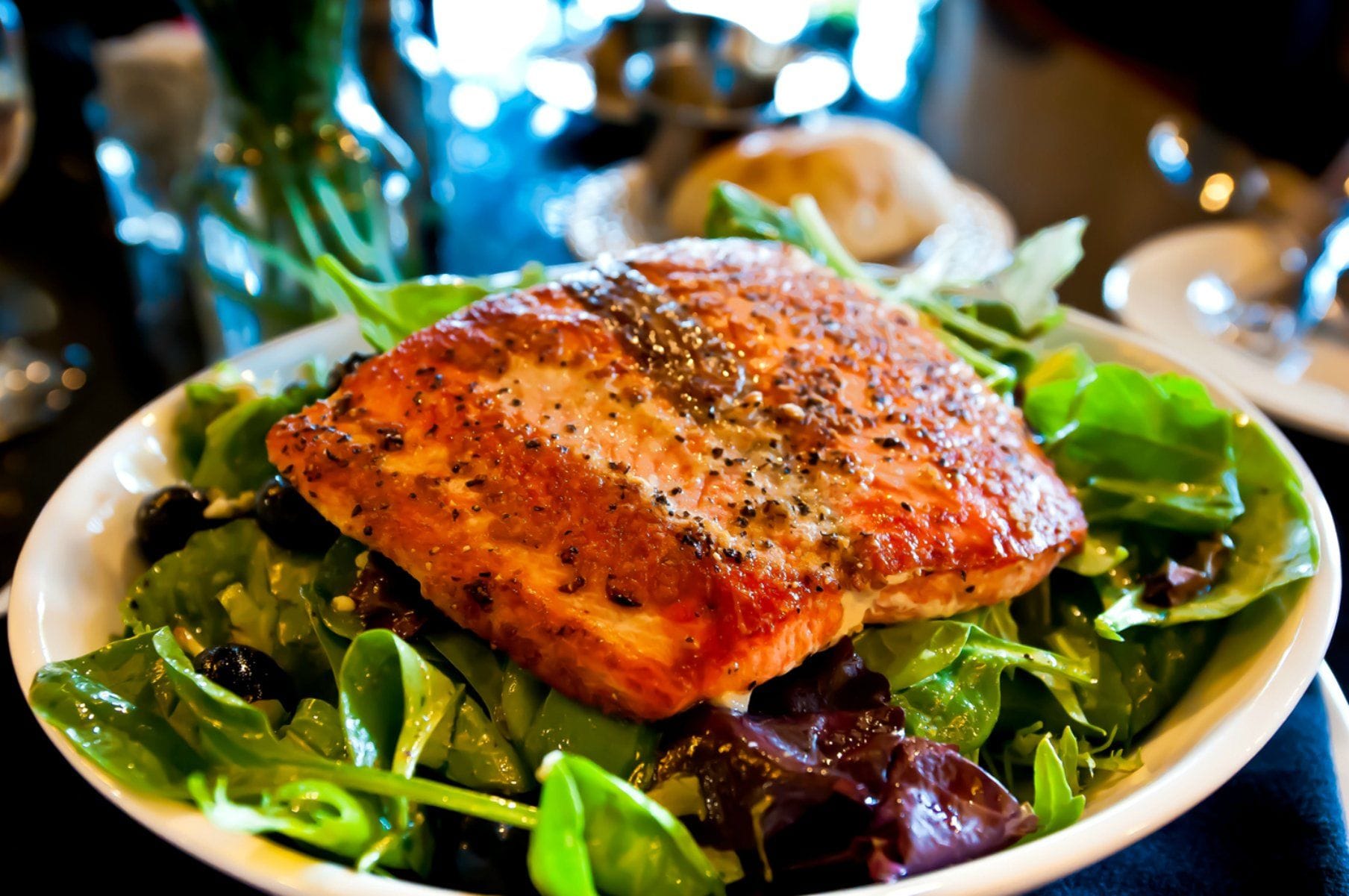 A plate with a piece of salmon on a bed of mixed greens.