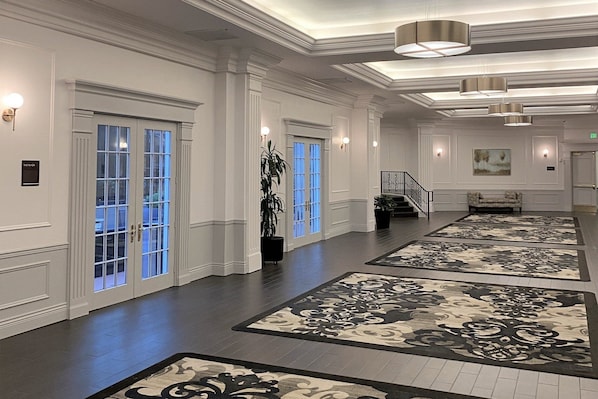 A spacious lobby with a grand staircase, large windows with blue-tinted glass, and decorative rugs on the floor. - Crowne Plaza Portland Downtown Convention Center by IHG (Portland)