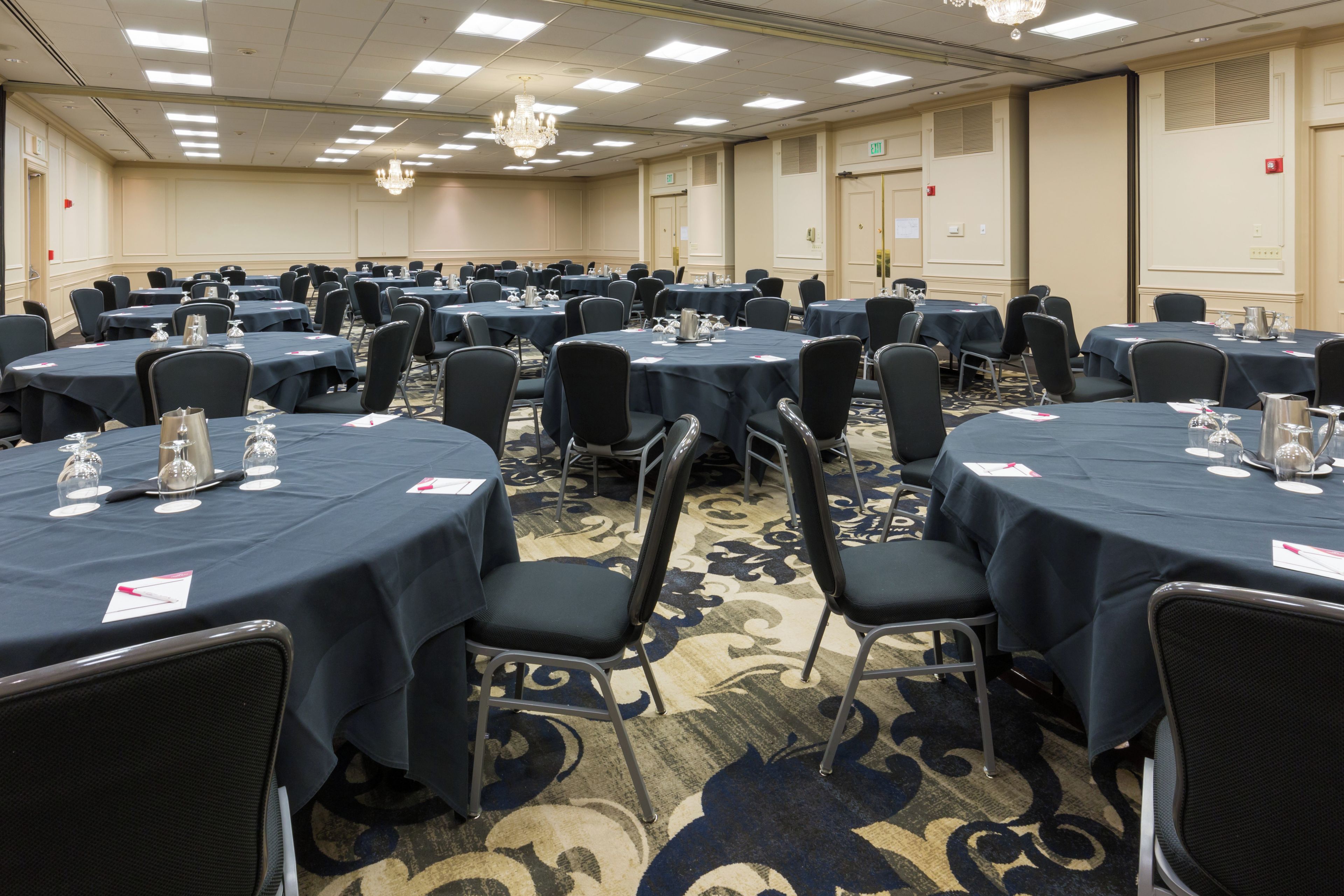 A conference room with multiple tables and chairs, equipped with water glasses and nameplates.