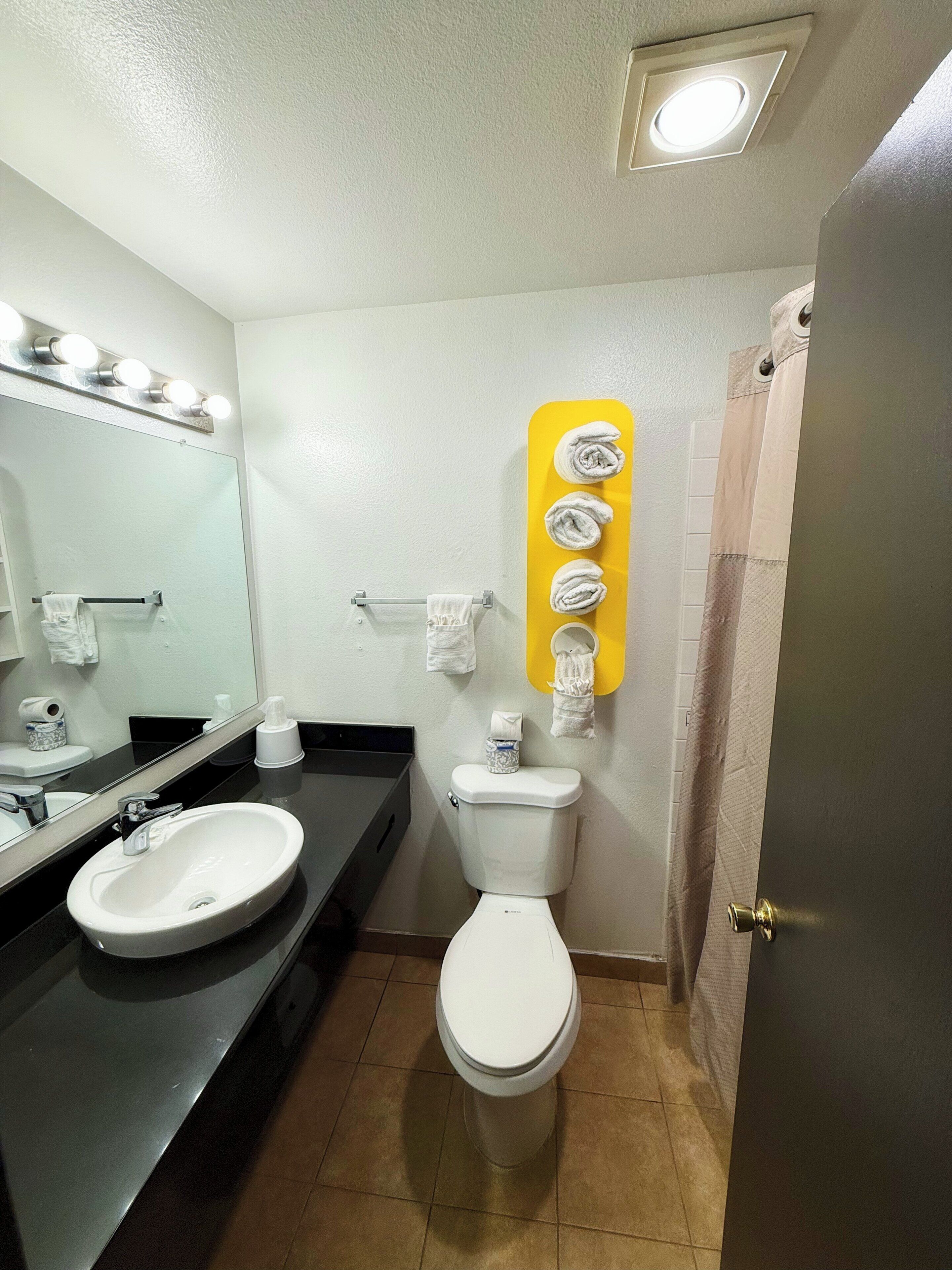A bathroom with a sink, mirror, toilet, and towel rack.