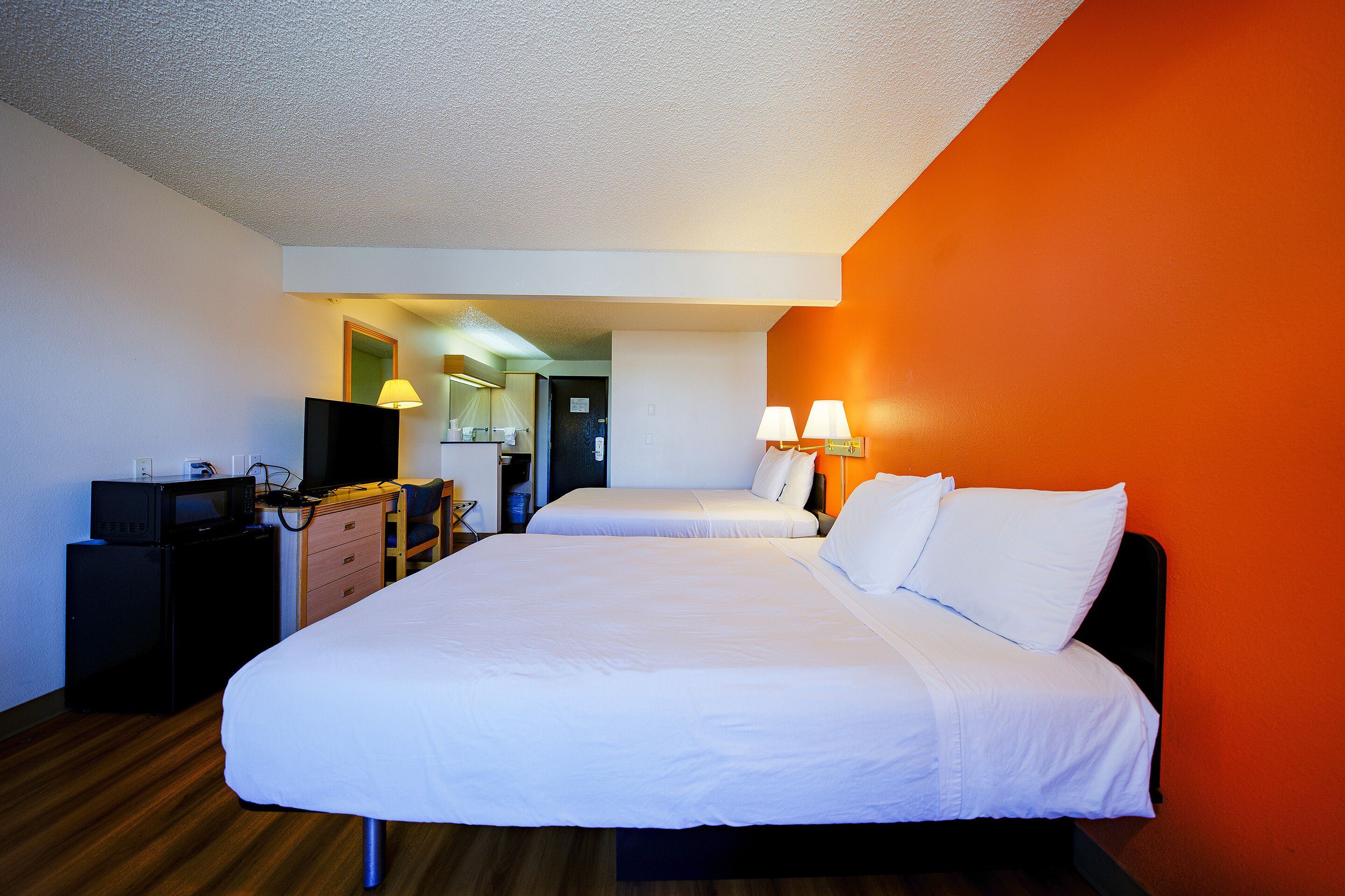 A hotel room with a large bed, a desk with a computer, and a television.