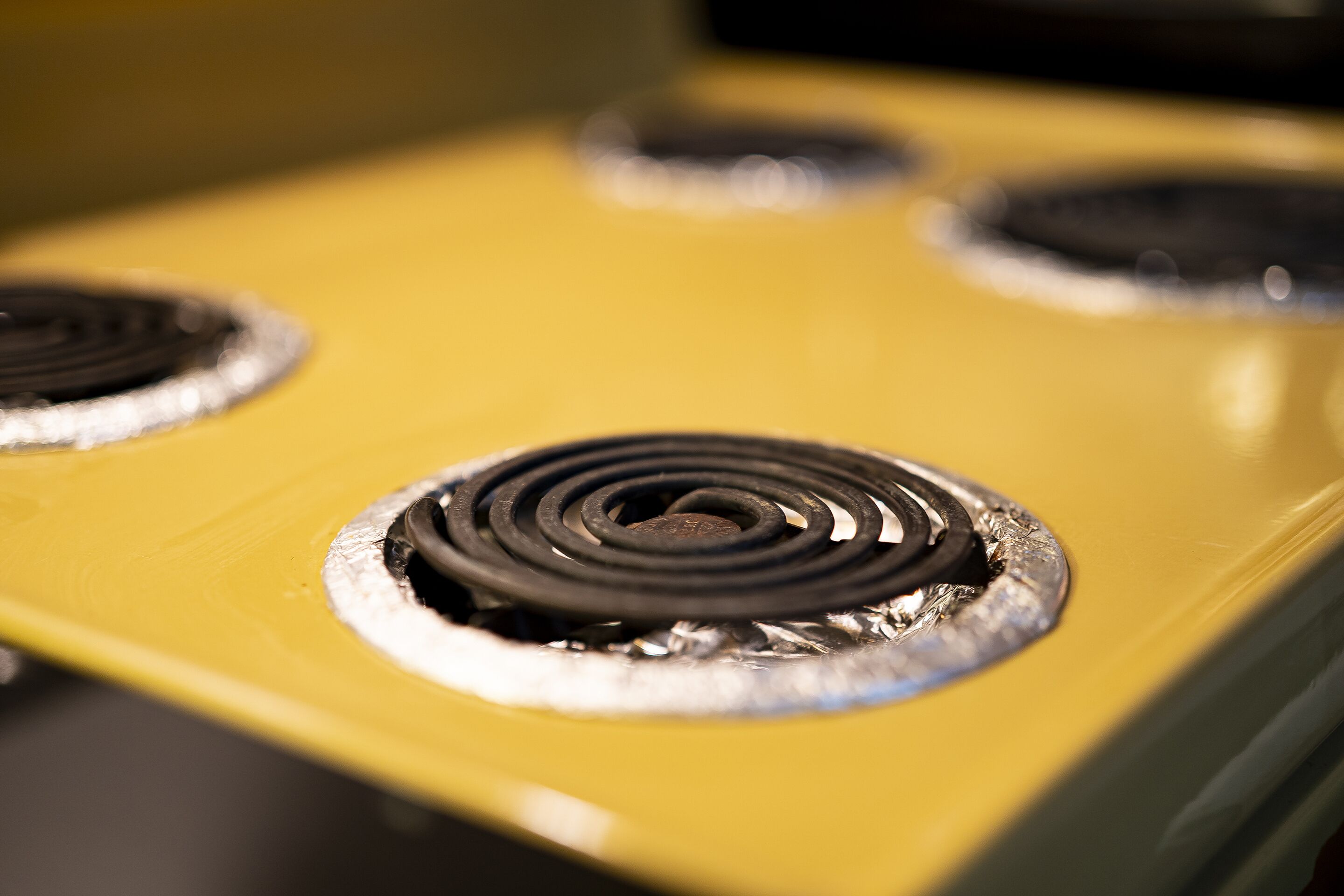 Une cuisinière jaune à quatre brûleurs.
