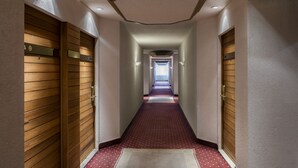 A hotel hallway with wooden paneling on the walls, a red carpet, and a view of the city in the distance. - Hôtels Gouverneur Montréal - Île Charron (Longueuil)