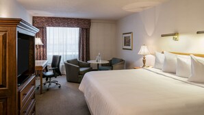 A hotel room with a bed, a desk, a chair, a television, and a lamp. - Hôtels Gouverneur Montréal - Île Charron (Longueuil)