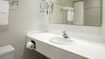 Une salle de bain moderne avec un lavabo blanc, des toilettes, un miroir et un rideau de douche.