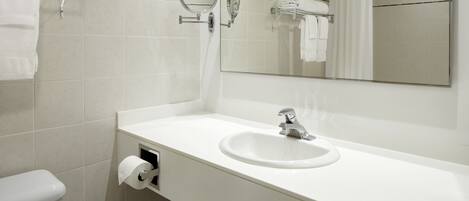 A modern bathroom with a white sink, a toilet, a mirror, and a shower curtain.