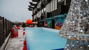A swimming pool area with a blue pool, red and white lounge chairs, and a large orange sun decoration.