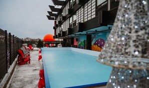 A swimming pool area with a blue pool, red and white lounge chairs, and a large orange sun decoration.
