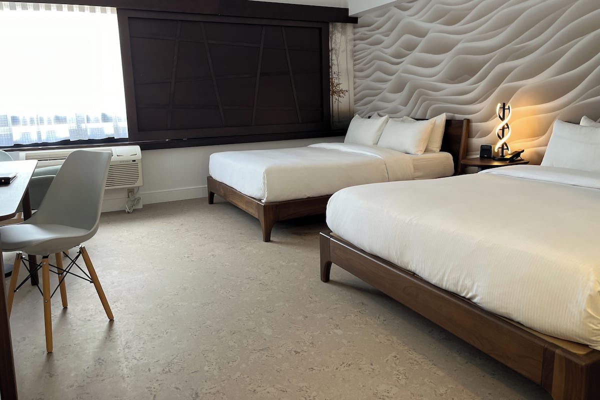 Une chambre d’hôtel avec deux lits, un bureau et une chaise.