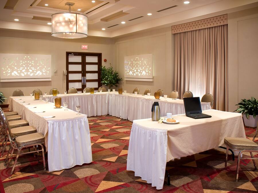 A conference room with long tables, chairs, and a laptop on one table.
