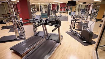 Une salle de sport équipée de tapis de course, d’appareils de musculation et d’un mur recouvert de miroirs.