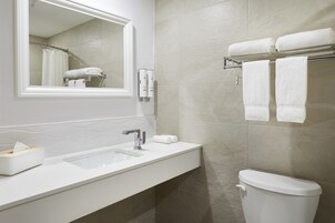 A modern bathroom with a white sink, mirror, and towel rack.