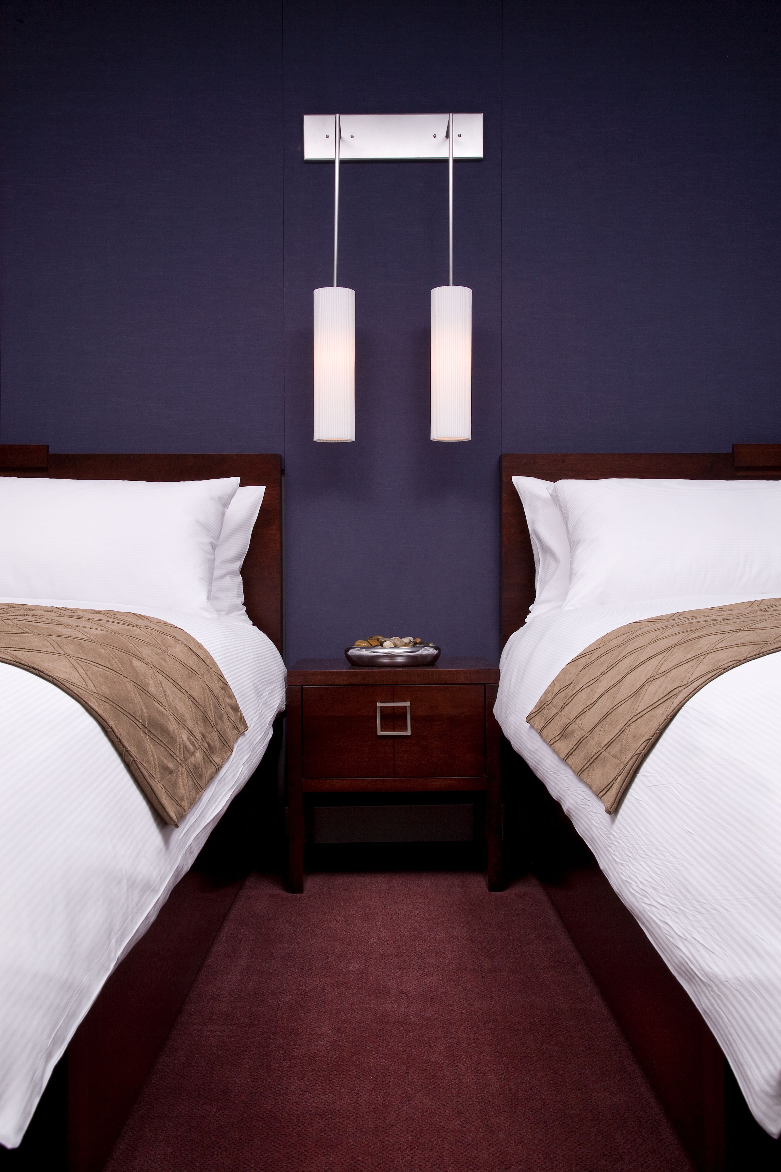 Ein Hotelzimmer mit zwei Betten, einem Nachttisch und einer wandmontierten Lampe.