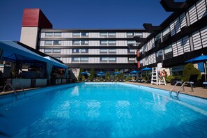 Una piscina al aire libre de temporada, sombrillas, tumbonas