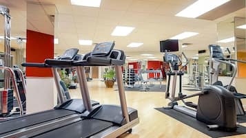 Un gimnasio con cintas de correr, elípticas y equipo de pesas.