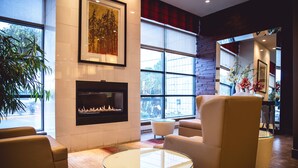 A modern lobby with a fireplace, comfortable seating, large windows, and a view of the outside.