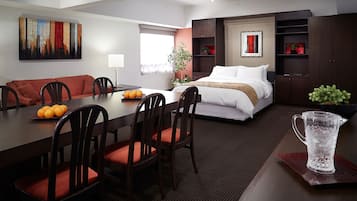 Une chambre d’hôtel moderne dotée d’un coin repas, d’un lit et d’une grande fenêtre.