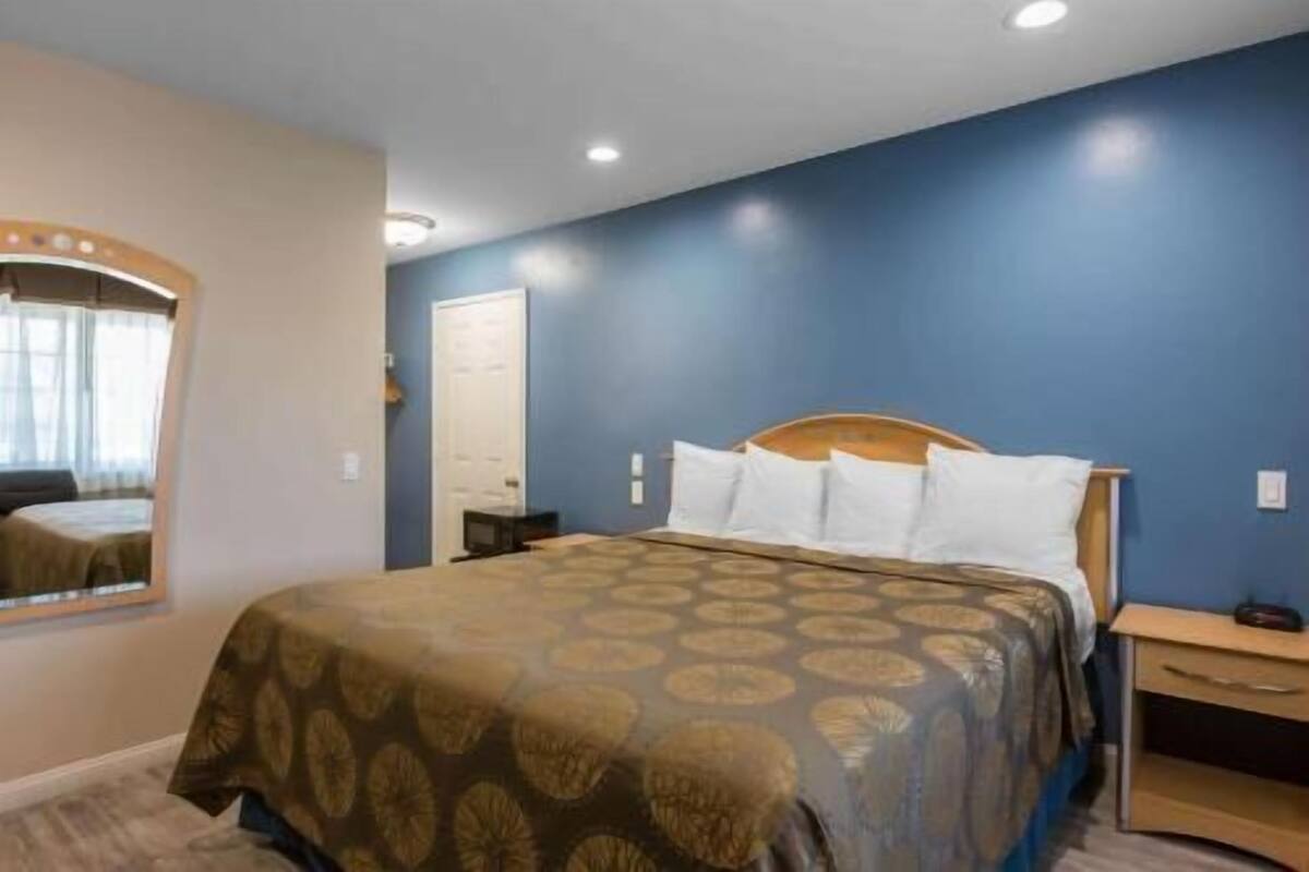 Una camera da letto con un letto, un comodino, uno specchio e una porta.