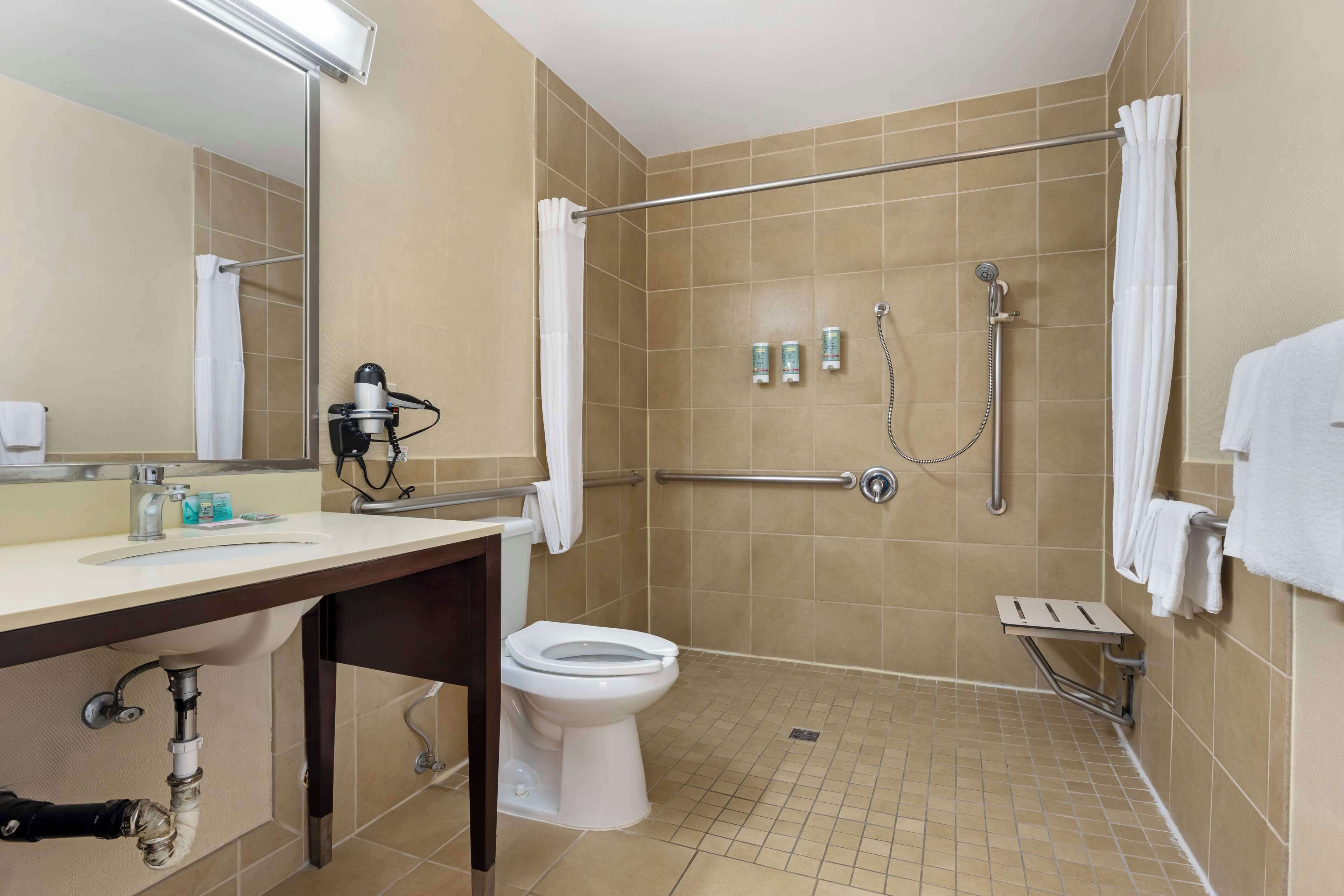 A bathroom with a shower, toilet, sink, and hand dryer.