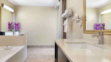 A modern bathroom with a bathtub, two sinks, a large mirror, and a towel rack.