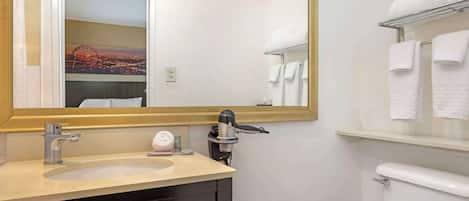 A bathroom with a sink, mirror, and toilet.