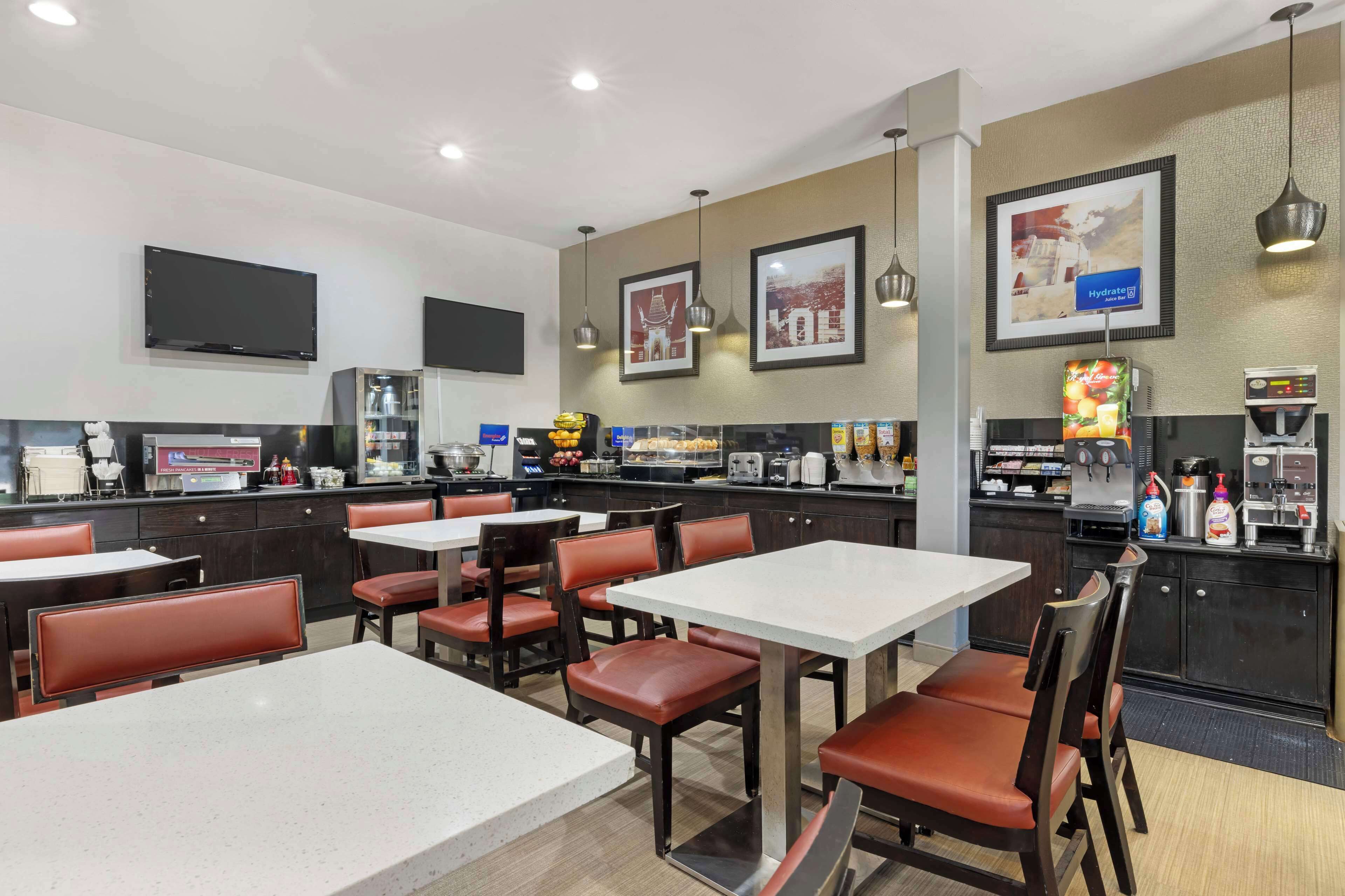 A restaurant with tables and chairs, a counter with food items, and a beverage dispenser.