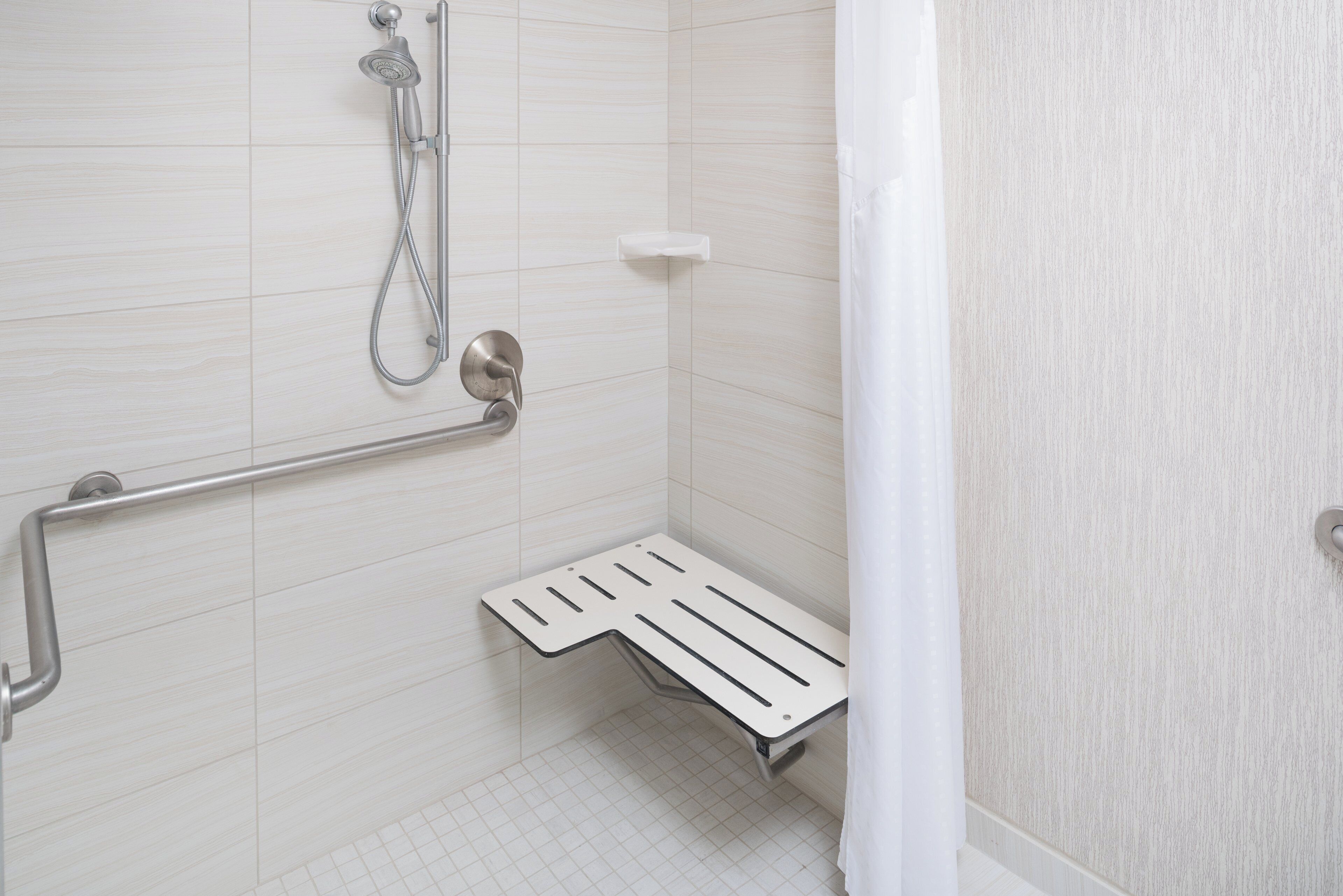 Un bagno dotato di doccia, maniglione e un piccolo gradino per facilitare l'accesso.