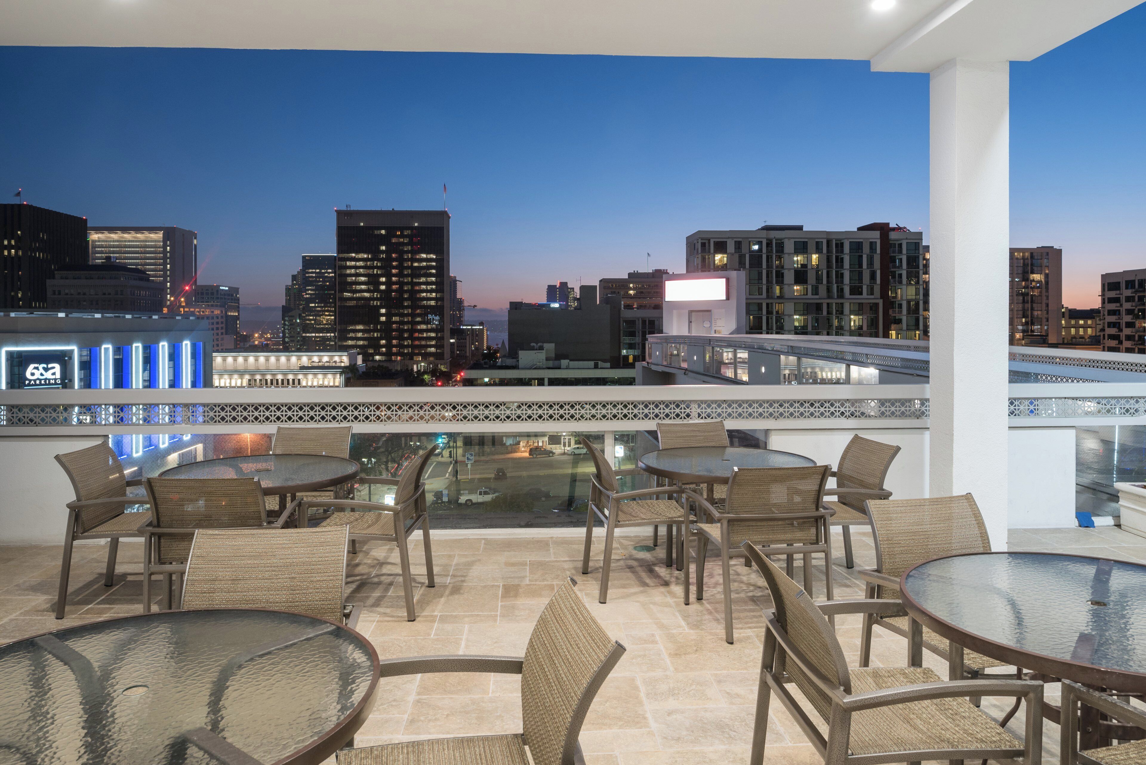 A rooftop terrace with outdoor seating and a city skyline view.