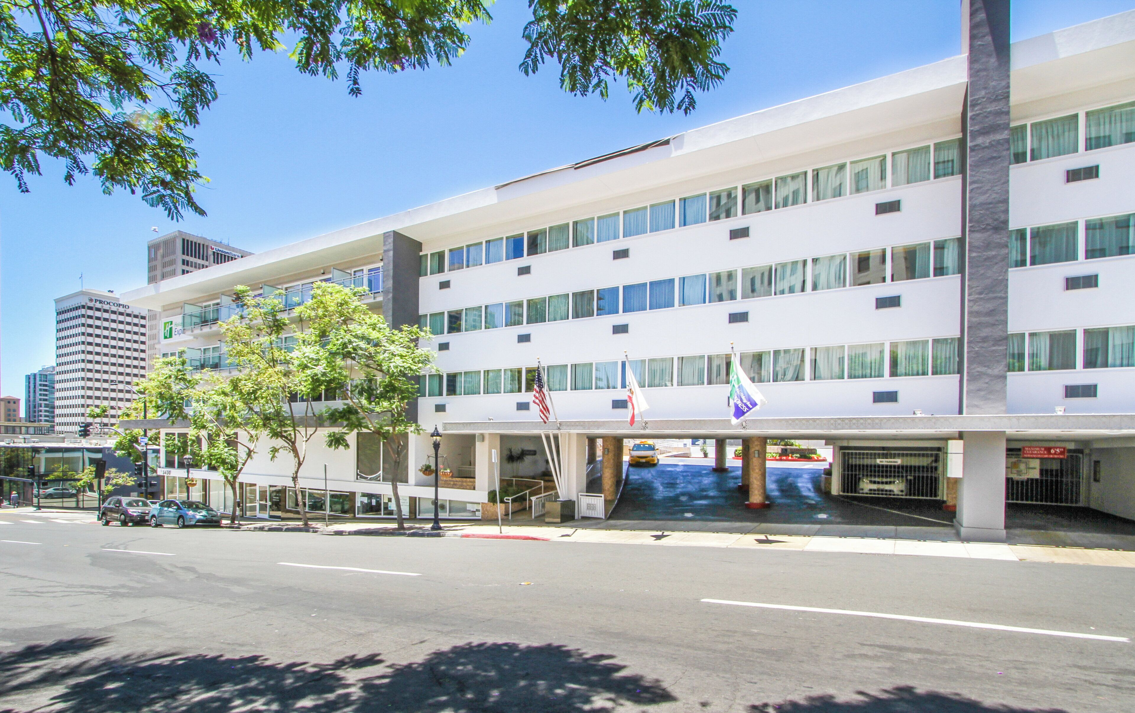 Un hotel moderno con fachada plana, varias ventanas y un estacionamiento al frente.