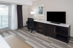 A hotel room with a bed, a desk with a chair, a TV, and a painting on the wall. - Holiday Inn Express San Diego Downtown by IHG (San Diego)