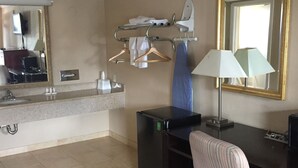 A hotel room with a desk, chair, and a mirror. - American Inn (Stockton)