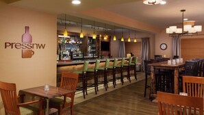 A bar area with a bar counter, multiple chairs, and hanging pendant lights. - DoubleTree by Hilton Portland - Tigard (Tigard)
