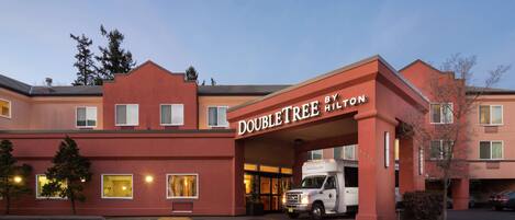 A DoubleTree by Hilton hotel with a red facade, a white entrance, and a parking lot.