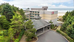 A hotel with a parking area, a covered entrance, and a view of the beach.