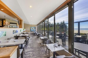 A restaurant with a view of the beach, featuring tables and chairs, and a bar area with taps. - Best Western Plus Agate Beach Inn (Newport)
