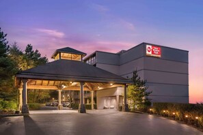 Een hotel met een overdekte ingang, een bord met 'Best Western Plus' en een parkeerplaats.