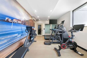 Een sportschool met loopbanden, elliptische trainers en een muurschildering.