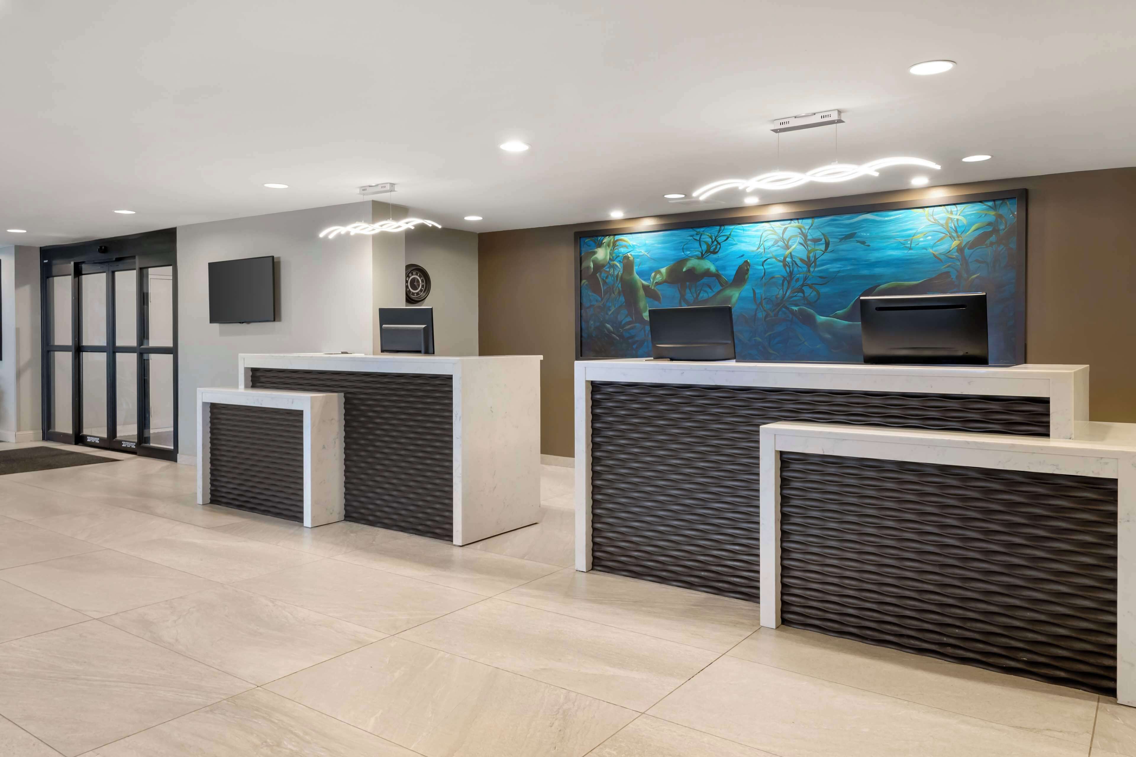A reception area with a modern design, featuring a reception desk, a clock, and a large aquarium wall.