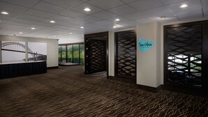 A hotel lobby with a patterned carpet, a large framed picture of a bridge, and a sign reading "SeaClass".