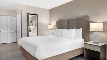 A hotel room with a large bed, bedside tables with lamps, a mirror, and a wardrobe.