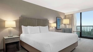 A hotel room with a large bed, two bedside tables, a chair, and a view of the outdoors.