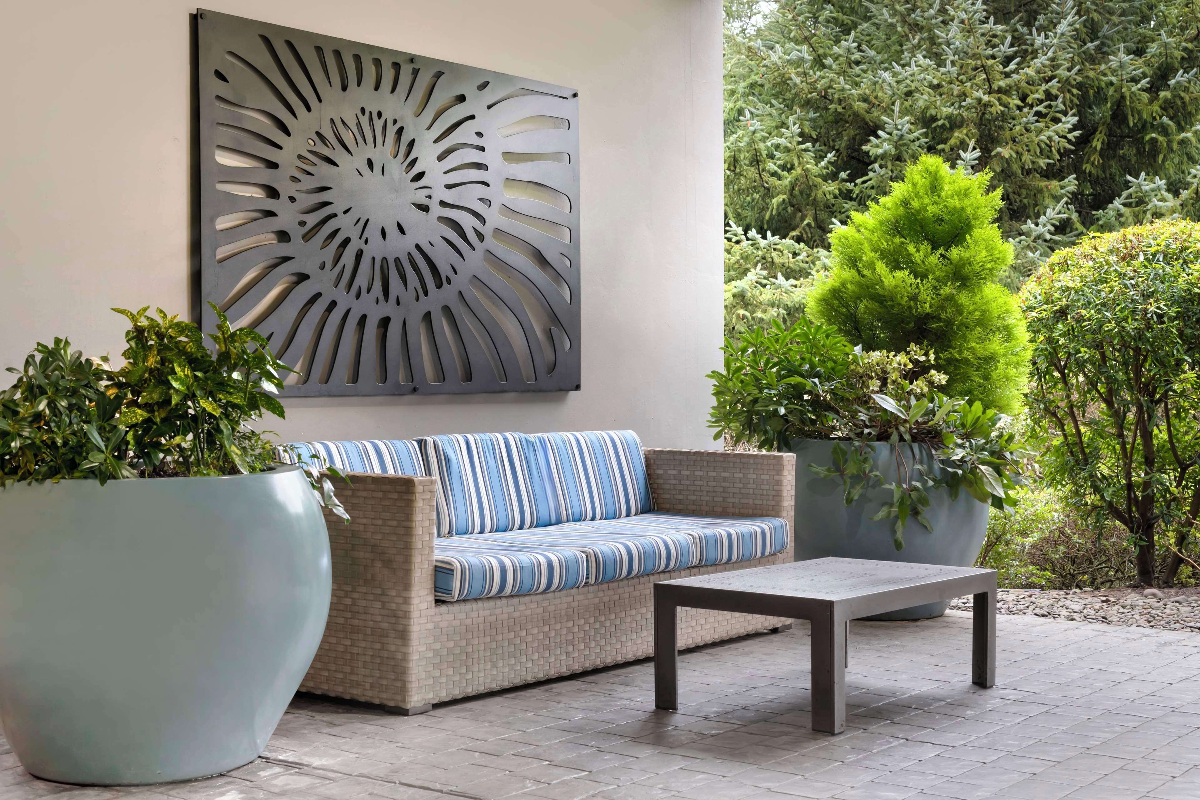 A patio area with a sofa, a table, and potted plants.