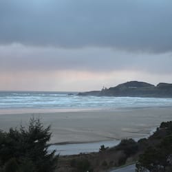 Enjoy a serene beachside escape with access to a wide, sandy beach and a scenic rocky outcrop in the distance.
