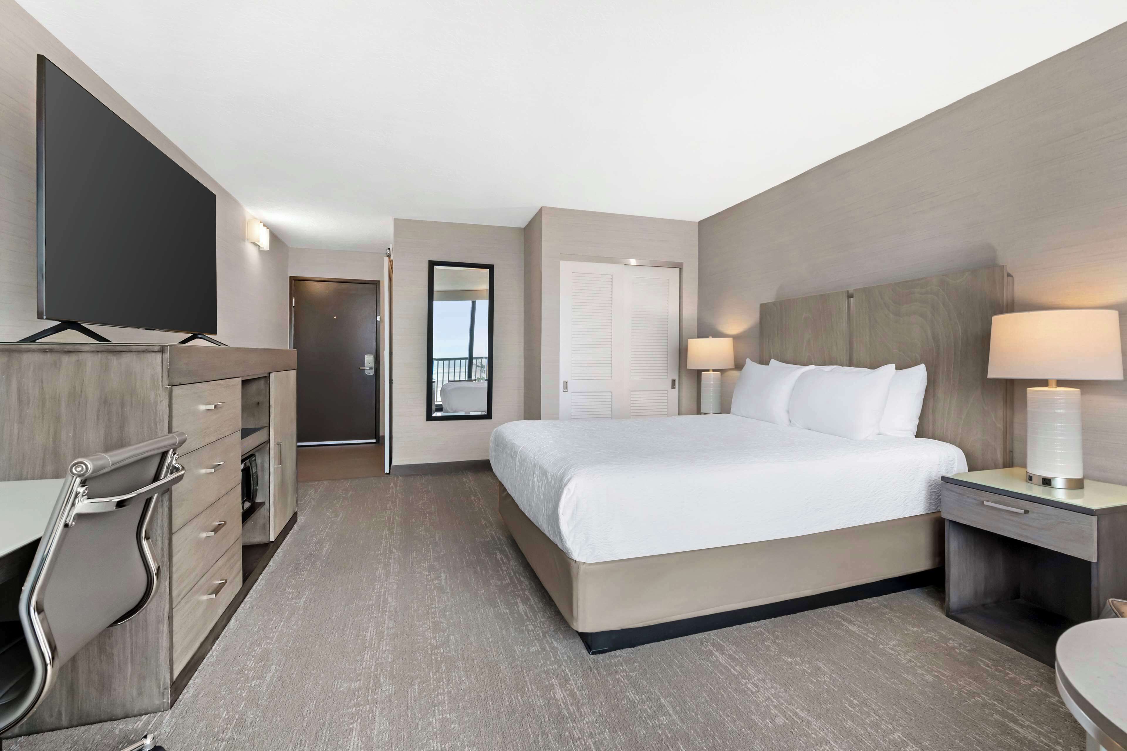 Habitación de hotel con cama, mesitas de noche, televisor y baño.