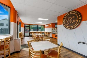 A restaurant interior with wooden tables and chairs, a pizza sign on the wall, and a view of the outside through large windows. - Days Inn by Wyndham Terrace (Terrace)