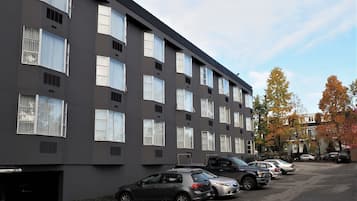 Un edificio de varios pisos con una fila de coches estacionados en la calle.