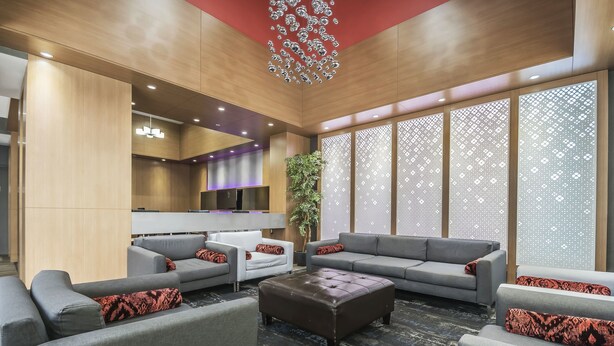 A modern lobby with grey sofas, a central ottoman, and a decorative ceiling. - Best Western Plus Vancouver Airport Hotel (Vancouver)