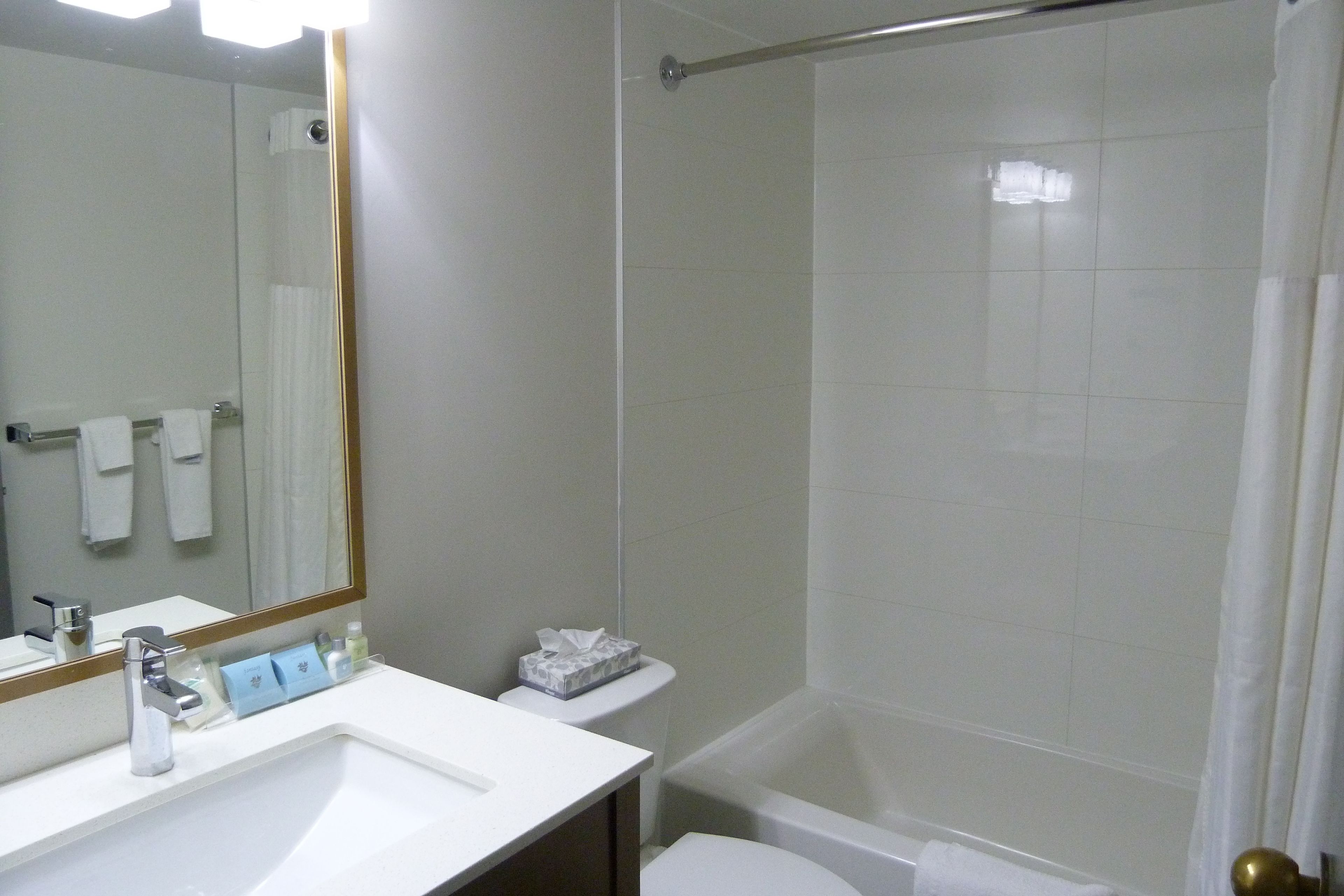 Ein Badezimmer mit Waschbecken, Spiegel, Toilette und Dusche.